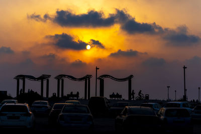 Cars on street against dramatic sky during sunset