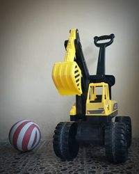 Close-up of yellow toy car against wall