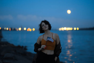 Woman standing at beach against sky during sunset