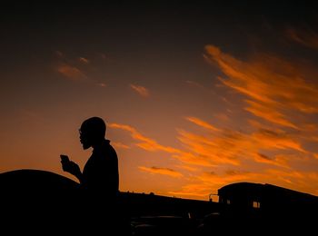 Silhouette man sitting against sky during sunset