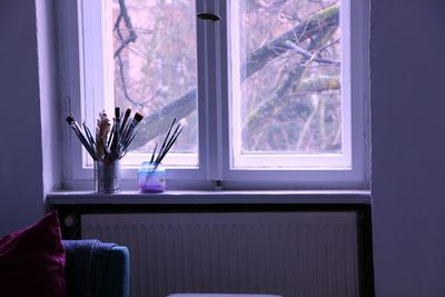 Paintbrushes in container on window at home