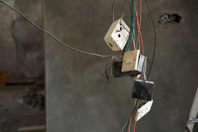 Close-up of electrical sockets with wire hanging  against wall