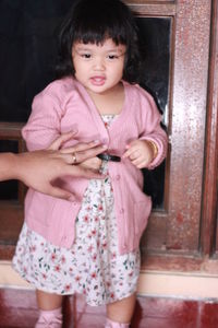 Cute girl holding pink while standing at home
