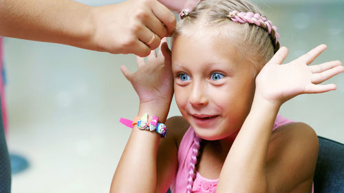 Beautiful blond girl, of seven years old, braided two pigtails, do a hairstyle with pink locks of