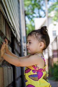 Side view of cute girl standing by wall on street