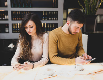 Couple using phone while sitting in cafe