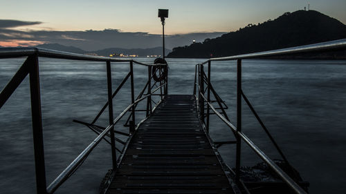 Pier over sea against sky during sunset