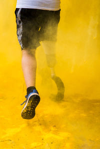 Low section of man with prosthetic leg in yellow powder paint
