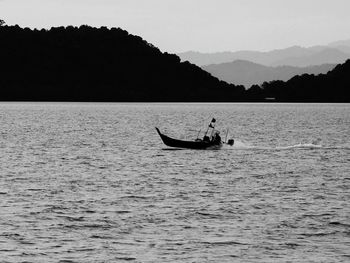 Silhouette man in boat on sea against sky