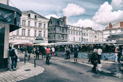 People walking on street in city against sky