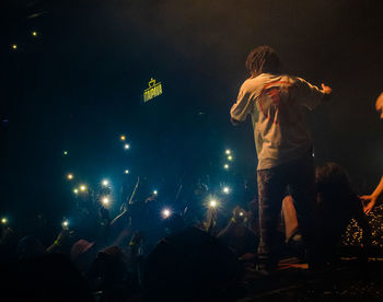 Rear view of people enjoying music concert at night