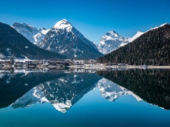 Scenic view of lake and snowcapped mountains against blue sky