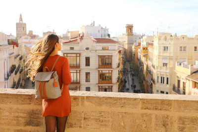 Rear view of woman standing against buildings in city