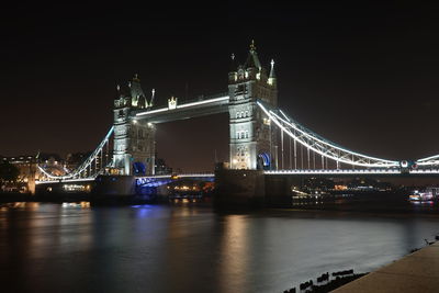 Illuminated tower bridge over thames river in city at night