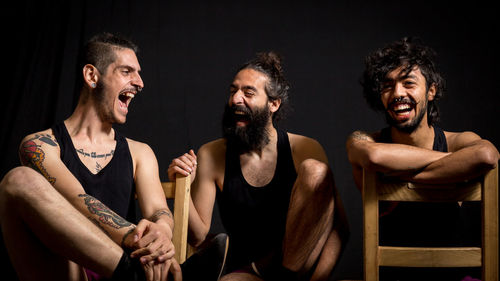 Happy friend sitting on chair against black background