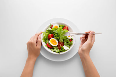 Midsection of woman holding bowl against white background