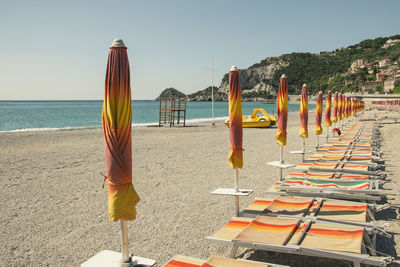 Deck chairs and parasols on beach against clear sky