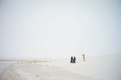 People on desert landscape against clear sky
