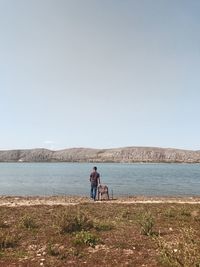 Rear view of couple standing by sea against clear sky