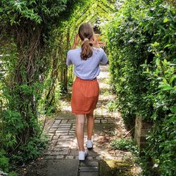 Full length rear view of woman walking on footpath