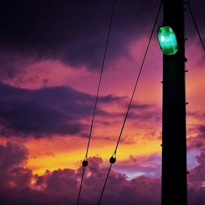 Low angle view of illuminated street light against cloudy sky