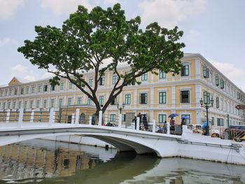 Arch bridge over canal by buildings in city against sky