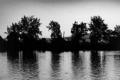 Silhouette trees by lake against sky