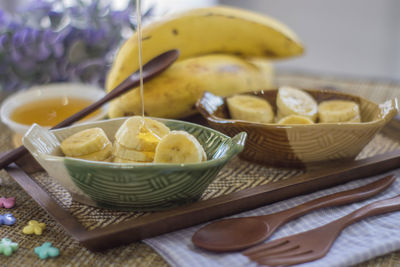 Close-up of honey being poured on banana sliced in bowl