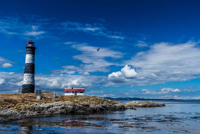 Lighthouse by sea against sky