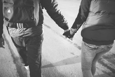 Rear view of couple holding hands and walking on street