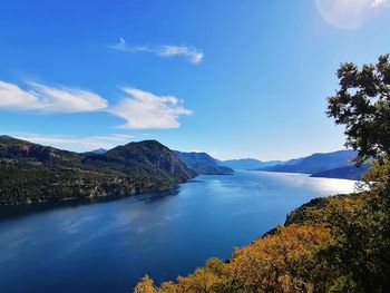 Scenic view of lake and mountains against blue sky