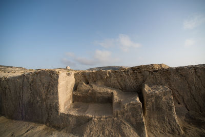 Stone wall on beach against sky