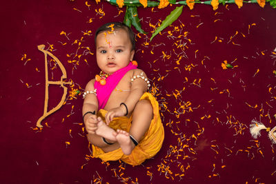 Cute indian boy dresses as lord rama with bow and flowers from top angle