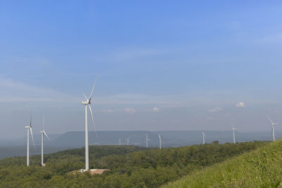 Wind turbines on field against sky