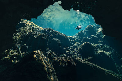 Low angle view of man scuba diving amidst rock formations in sea