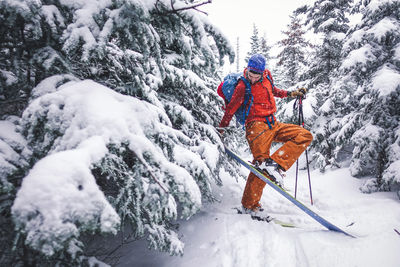 A man removes his skiing skins from his skis during a snowy tour