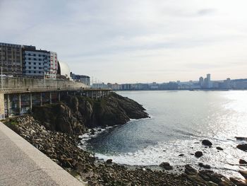 Buildings by sea against sky