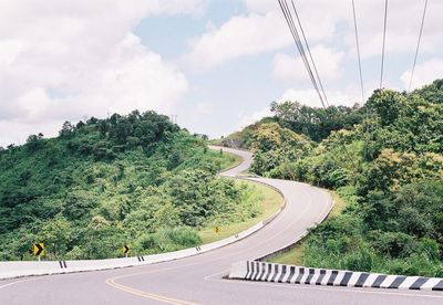Road by trees against sky