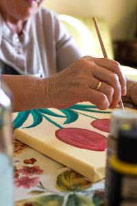 Midsection of person holding painting on table