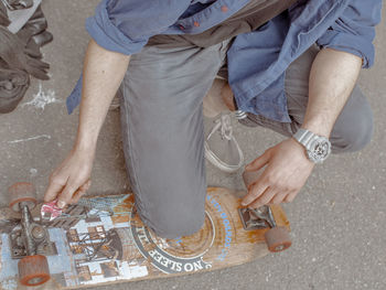 Low section of man crouching by skateboard