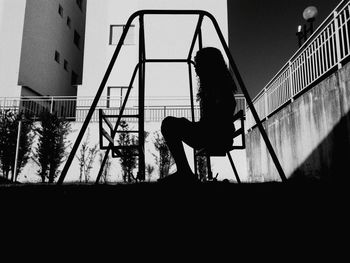 Silhouette woman standing on steps at playground against clear sky