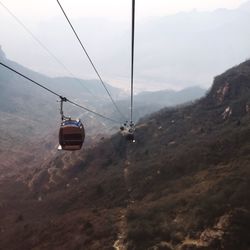 Overhead cable car over mountains against sky