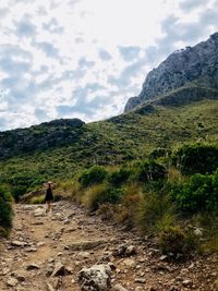 Rear view of man walking on mountain against sky