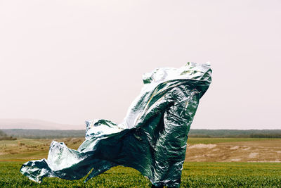 Side view of person with shiny foil on field against clear sky