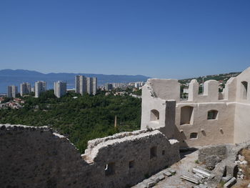 Buildings in city against clear blue sky