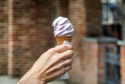 Woman holding ice cream cone, hand in frame