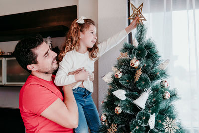 Happy father and daughter decorating christmas tree