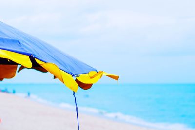 Yellow umbrella on beach against sky