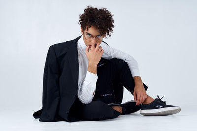 Young man sitting on wall against white background