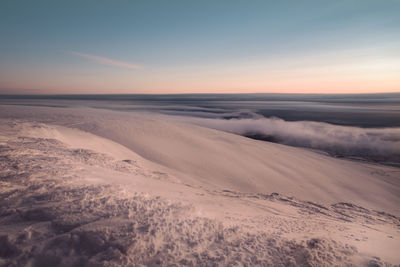 Scenic view of snow covered land against sky during sunset